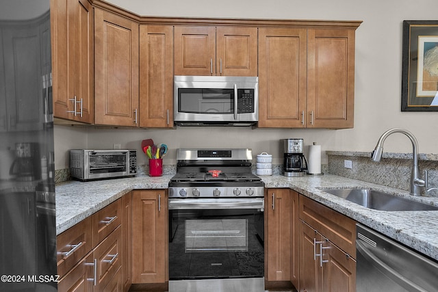 kitchen featuring light stone counters, sink, and appliances with stainless steel finishes