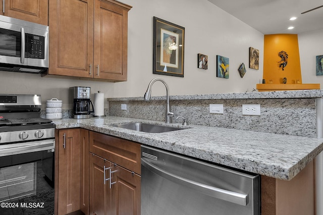 kitchen with backsplash, light stone counters, sink, and stainless steel appliances