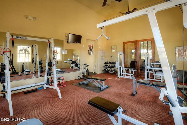 workout area featuring carpet flooring, ceiling fan, and a high ceiling