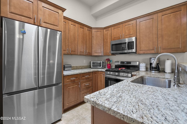 kitchen featuring light stone countertops, sink, light tile patterned floors, and appliances with stainless steel finishes