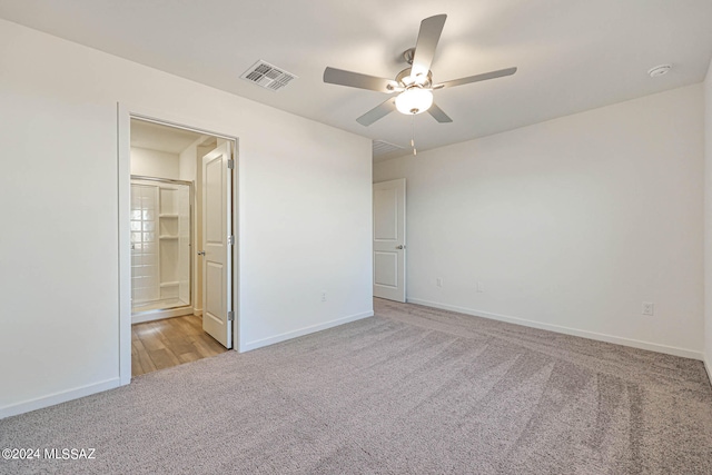 unfurnished bedroom featuring ceiling fan, ensuite bath, and light colored carpet