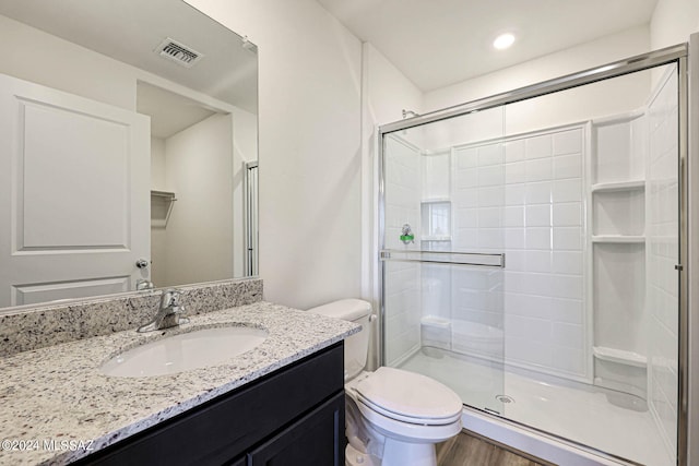 bathroom featuring toilet, vanity, hardwood / wood-style flooring, and a shower with door