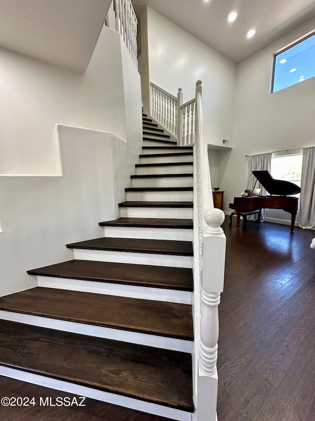 stairs featuring wood-type flooring and a high ceiling