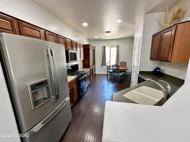 kitchen with a textured ceiling, stainless steel appliances, sink, and dark hardwood / wood-style floors