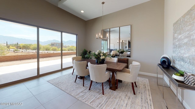 dining area with a mountain view, light tile patterned floors, a towering ceiling, and an inviting chandelier