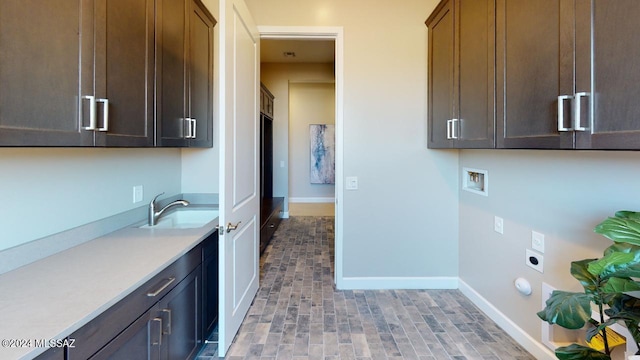 clothes washing area featuring electric dryer hookup, hookup for a washing machine, sink, and cabinets