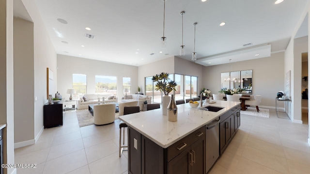 kitchen featuring sink, decorative light fixtures, stainless steel dishwasher, and an island with sink