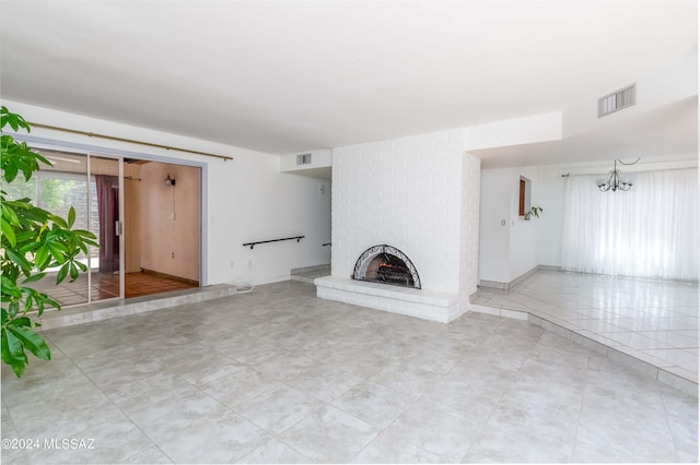 unfurnished living room with a fireplace and a notable chandelier