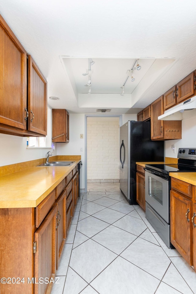 kitchen featuring rail lighting, stainless steel appliances, a raised ceiling, sink, and light tile patterned floors