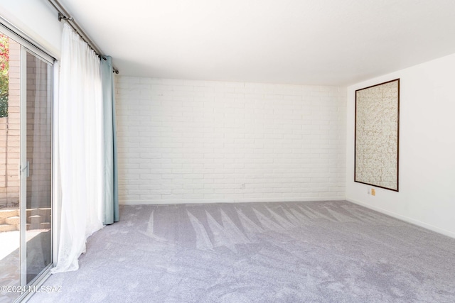 spare room featuring carpet and brick wall