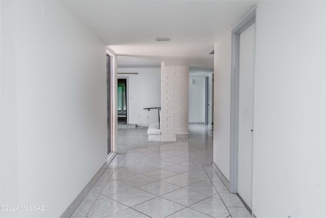 hallway with ornate columns and light tile patterned floors