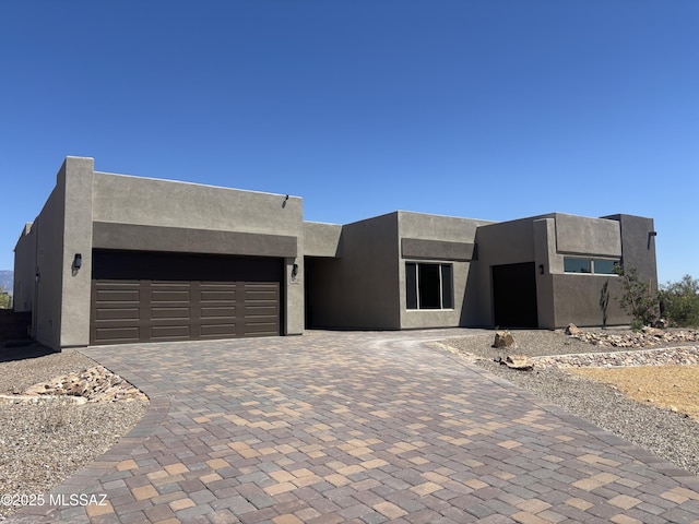 view of front facade featuring stucco siding, decorative driveway, and an attached garage