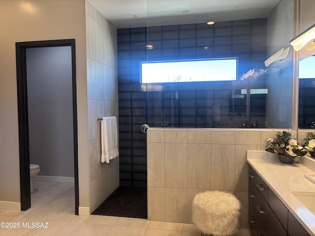 bathroom featuring tile patterned flooring, a walk in shower, tile walls, toilet, and vanity