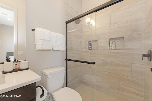 bathroom with vanity, toilet, and a shower with shower door