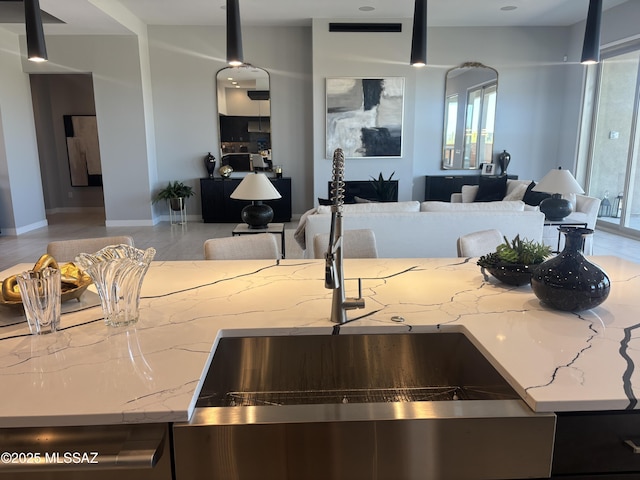 kitchen featuring open floor plan, a wealth of natural light, light stone countertops, and a sink