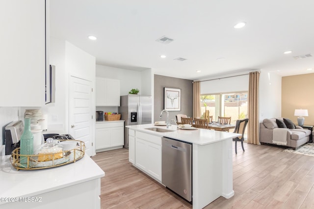 kitchen with sink, light hardwood / wood-style flooring, stainless steel appliances, white cabinets, and a center island with sink