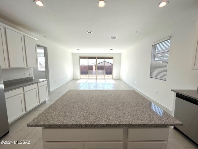 kitchen featuring white cabinets, light tile patterned floors, stainless steel dishwasher, and a kitchen island