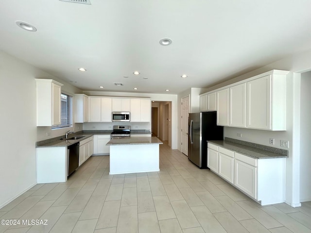 kitchen featuring appliances with stainless steel finishes, white cabinetry, a kitchen island, and sink