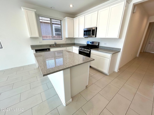 kitchen featuring a kitchen island, light stone counters, white cabinetry, and stainless steel appliances