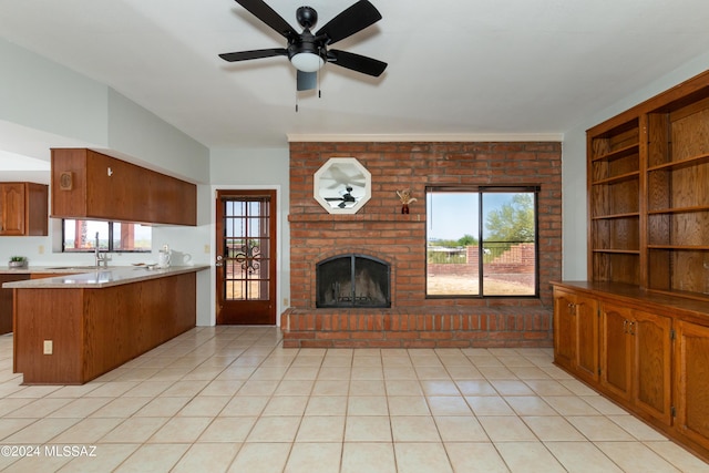 kitchen with ceiling fan, sink, a wealth of natural light, kitchen peninsula, and a fireplace