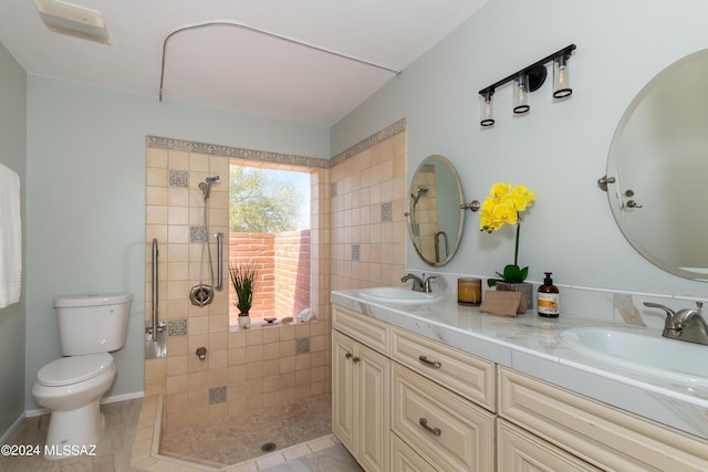 bathroom with tiled shower, vanity, tile patterned floors, and toilet