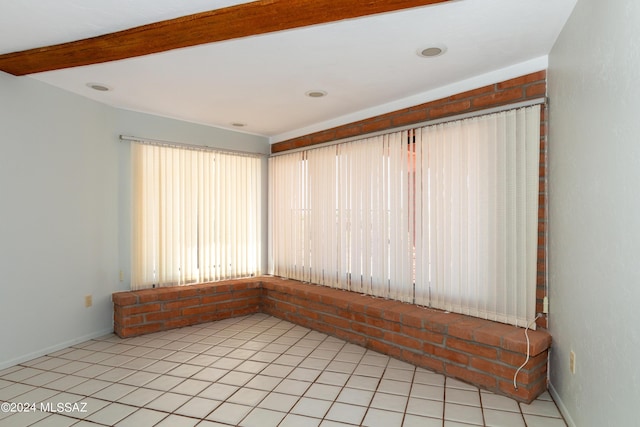 spare room with beamed ceiling and light tile patterned floors