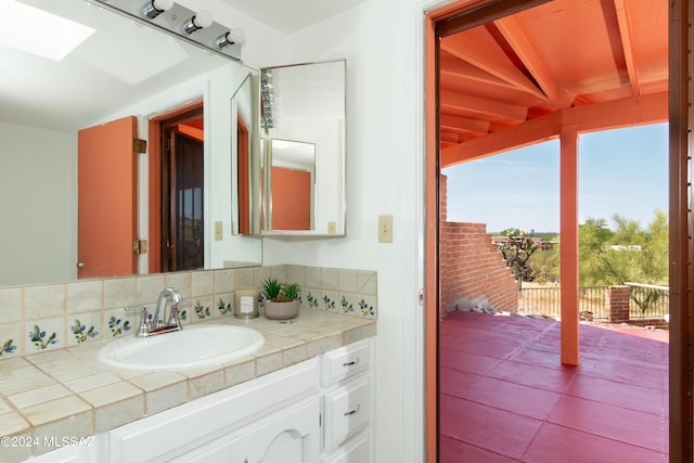 bathroom featuring tasteful backsplash, a skylight, and vanity