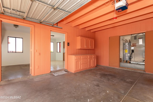 garage featuring heating unit, a garage door opener, wood walls, and water heater