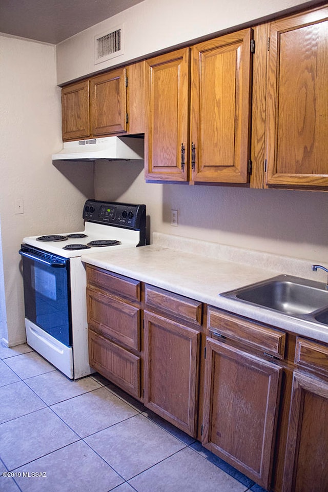 kitchen featuring sink, white electric range, and light tile patterned floors