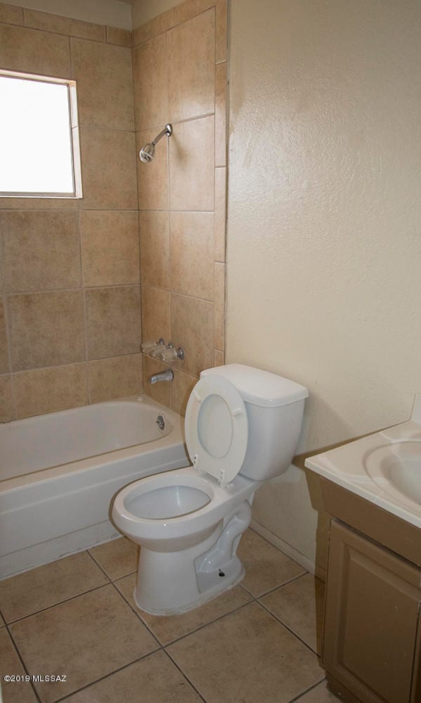 full bathroom with tile patterned flooring, tiled shower / bath combo, toilet, and vanity