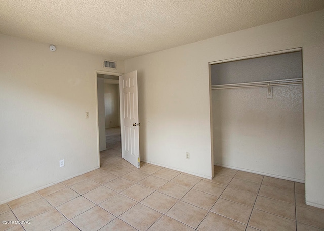 unfurnished bedroom featuring a closet, light tile patterned floors, and a textured ceiling