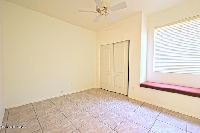 unfurnished bedroom with a closet, ceiling fan, and light tile patterned floors