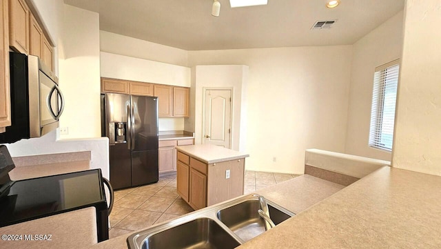 kitchen featuring a center island, light tile patterned floors, sink, stainless steel appliances, and light brown cabinets