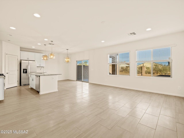 unfurnished living room with a chandelier, sink, and a wealth of natural light