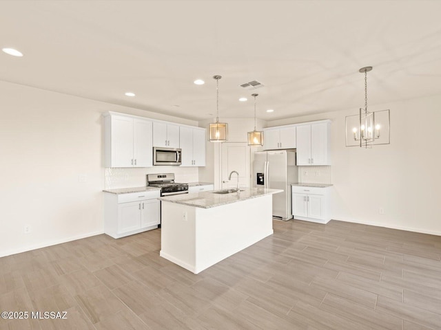 kitchen with appliances with stainless steel finishes, hanging light fixtures, and white cabinets