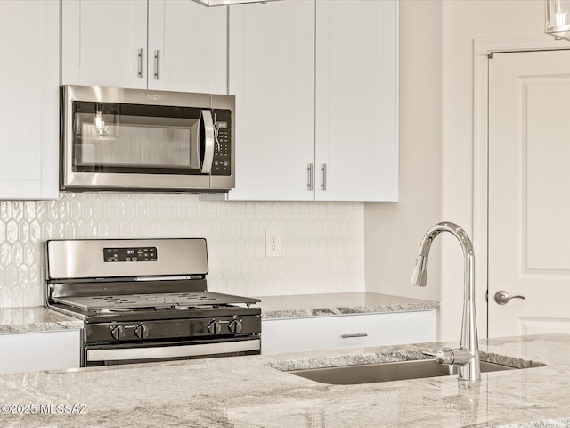 kitchen featuring white cabinetry, stainless steel appliances, light stone countertops, and sink