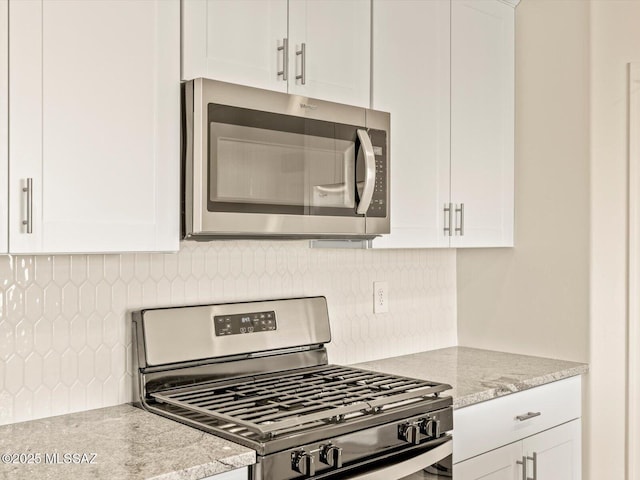 kitchen featuring light stone counters, stainless steel appliances, decorative backsplash, and white cabinets