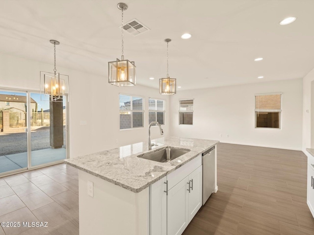 kitchen with pendant lighting, sink, white cabinetry, an island with sink, and stainless steel dishwasher