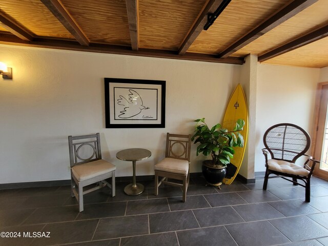 sitting room featuring beam ceiling, wooden ceiling, and dark tile patterned floors