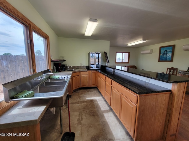 kitchen featuring kitchen peninsula, sink, and a wall unit AC