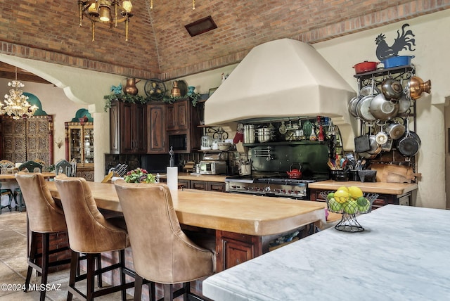 kitchen featuring butcher block countertops, brick ceiling, dark brown cabinets, custom exhaust hood, and appliances with stainless steel finishes