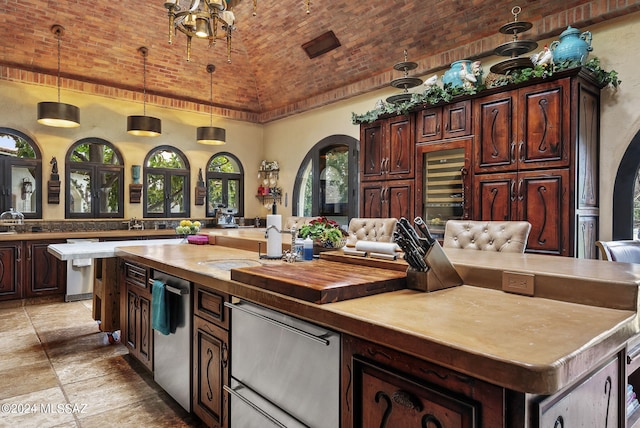 kitchen with high vaulted ceiling, pendant lighting, brick ceiling, a center island with sink, and dark brown cabinets