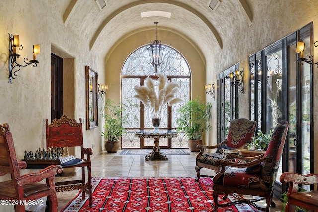 sitting room with high vaulted ceiling and an inviting chandelier