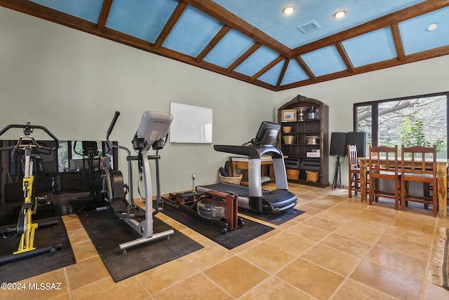 exercise room featuring light tile patterned floors and high vaulted ceiling