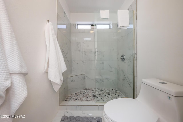 bathroom with a tile shower and toilet