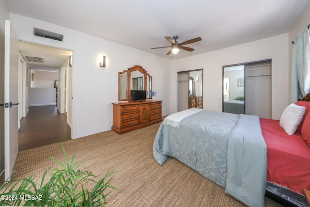 bedroom featuring ceiling fan, wood-type flooring, and multiple closets