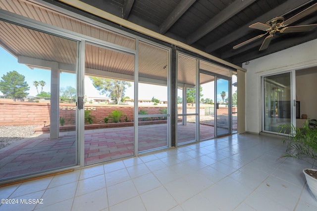 unfurnished sunroom featuring ceiling fan and beam ceiling