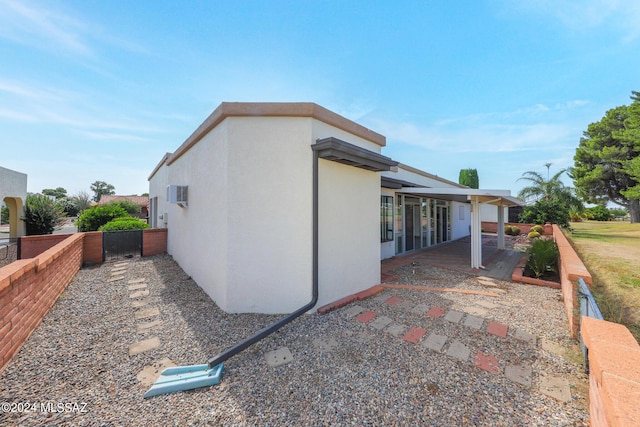 view of property exterior featuring a wall mounted air conditioner and a patio