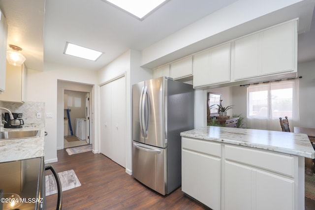 kitchen with white cabinets, dark hardwood / wood-style floors, stainless steel refrigerator, and sink