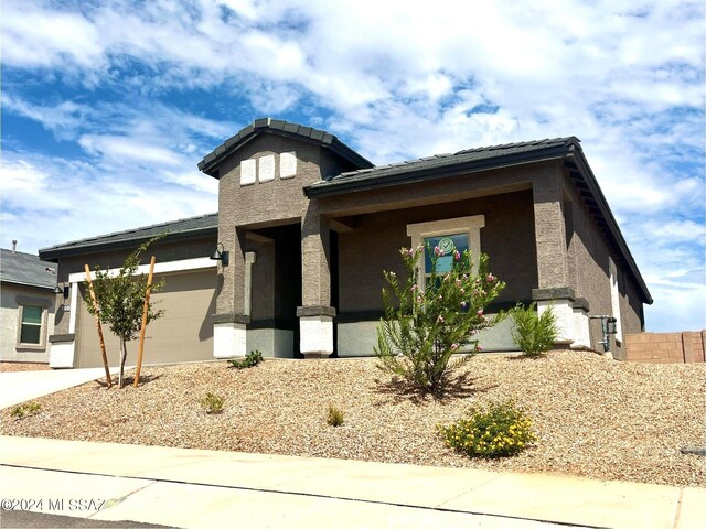 prairie-style home with concrete driveway, an attached garage, and stucco siding